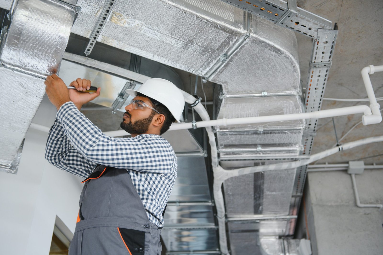 An Indian worker inspects the ventilation system in an office building.